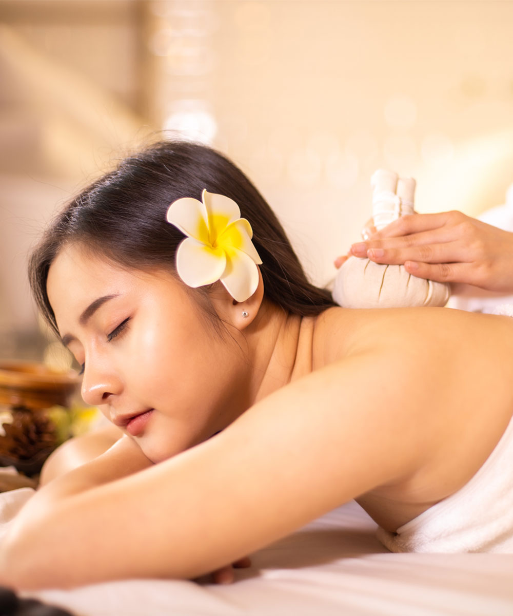 A pretty woman getting a relaxing body massage with Thai herbal ball compress